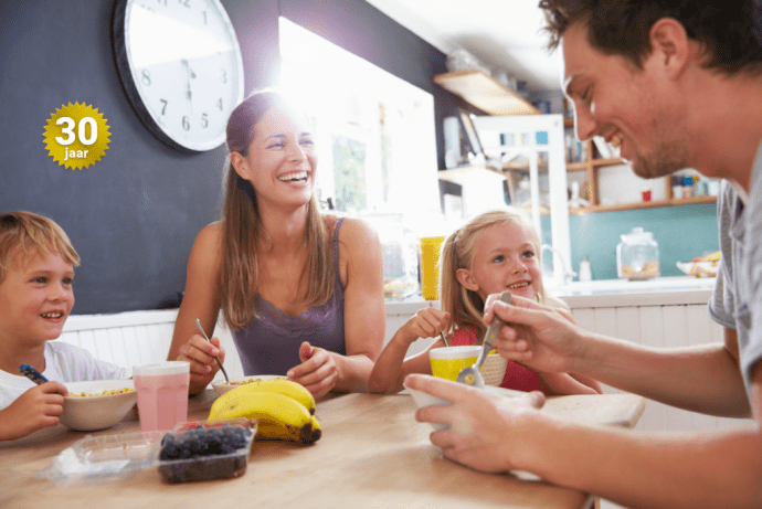 Une famille avec deux enfants souriants au petit dÃ©jeuner
