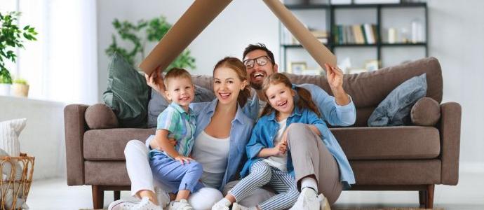 Eine glückliche Familie sitzt in ihrem feuchtigkeitsfreien Haus mit einem Pappdach über dem Kopf auf dem Boden vor dem Sofa